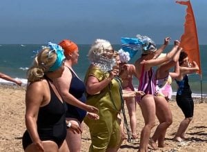 Eight women in costume dancing on the beach