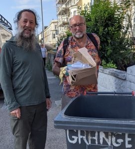 Ian dropping recycling waste into Garry's bin